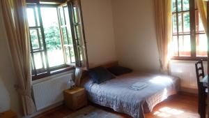 ein kleines Schlafzimmer mit einem Bett und zwei Fenstern in der Unterkunft Ropki Dwór RAJDANY in Ropki