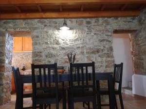 uma sala de jantar com uma parede de pedra e uma mesa e cadeiras em Casa da Figueirinha em Casais dos Monizes
