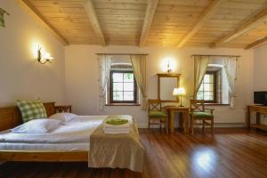 a bedroom with a bed and a table and two windows at Pensjonat Akacja in Kudowa-Zdrój