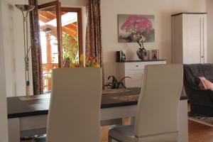 a dining room with a table and two white chairs at Auszeit-Wohnungen in Aidenbach