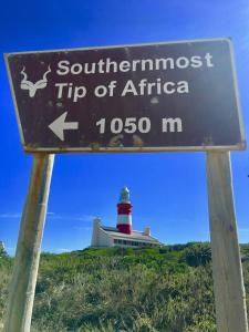 a street sign with a lighthouse in the background at Agulhasbestview in Agulhas