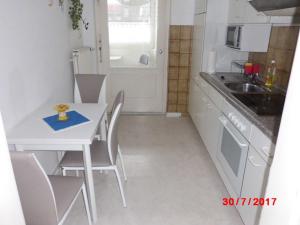 eine kleine Küche mit einem weißen Tisch und Stühlen in der Unterkunft Apartment Zur Kogge in Wilhelmshaven