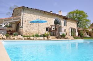 a house with a swimming pool and an umbrella at Chambre d'hotes Lencouet in Feugarolles