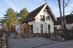 ein weißes Haus mit einer Steinmauer in der Unterkunft Refugium auf Usedom in Ostseebad Karlshagen