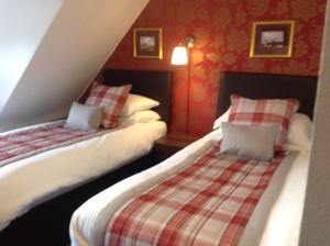 duas camas num quarto com paredes vermelhas em Royston Guest House Inverness em Inverness
