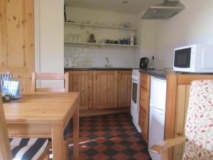 a kitchen with a wooden table and a microwave at Carpenter's Cottage in Pocklington