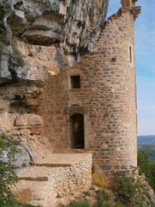 un viejo edificio de piedra en un acantilado con una puerta en la chomiarde, en Saint-Médard-de-Presque