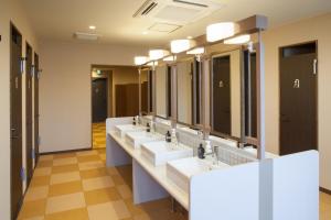 a row of sinks in a bathroom with mirrors at Kanazawa Capsule Hotel Musashimachi in Kanazawa