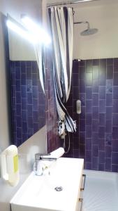 W łazience znajduje się umywalka i prysznic z fioletowymi kafelkami. w obiekcie La Cigalière w mieście Le Beausset