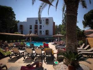 un grupo de personas sentadas en sillas de césped junto a una piscina en Hotel Aquarius en Canet-en-Roussillon