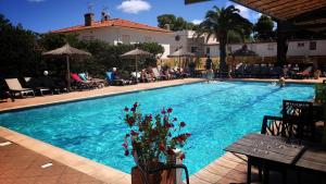 a swimming pool with people sitting in chairs around it at Hotel Aquarius in Canet-en-Roussillon