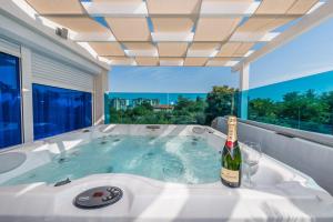 a hot tub with a bottle of wine and a glass at Luxury Apartments Villa Morea in Zadar