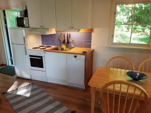 eine Küche mit weißen Geräten und einem Holztisch in der Unterkunft Svalemåla Stugby in Bräkne-Hoby