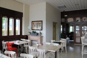 a restaurant with tables and white chairs and windows at Hotel Montero in Mondoñedo