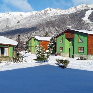 un groupe de maisons dans la neige avec des montagnes enneigées dans l'établissement Cabañas Ruca Carel, à San Carlos de Bariloche