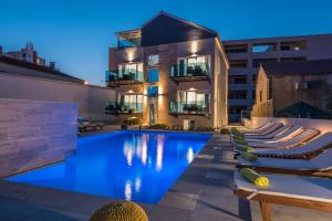 - une piscine avec des chaises longues devant un bâtiment dans l'établissement Luxury Apartments Villa Morea, à Zadar