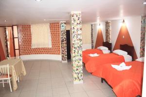 Habitación de hotel con 2 camas y mesa en Hotel Los Gladiolos, en Cajamarca