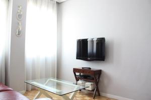 een woonkamer met een glazen tafel en een tv aan de muur bij MADRID CENTER, WIFI (RETIRO IBIZA) in Madrid