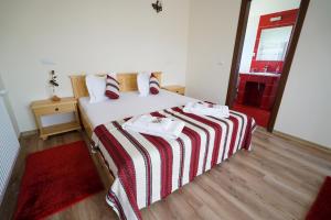 a bedroom with a bed with a red and white striped blanket at Casa Bunicii in Moisei