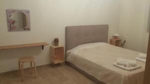 a bedroom with a bed and a stool and a mirror at Menehuna Heartmade Maison in Chorefto