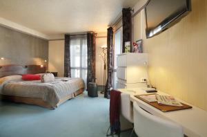 a bedroom with a bed and a desk with a computer at Hotel De Gramont in Pau