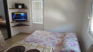 a small room with a bed and a tv at Apartments Diva in Dobra Voda