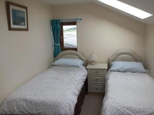 two beds in a bedroom with a mirror and a window at Lazy Daisys in Langsett