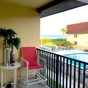 a red chair sitting on a balcony overlooking a pool at Beautiful Ocean view Townhouse in Cocoa Beach