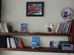 a shelf with books and a clock on a wall at Casa Havana in Costinesti