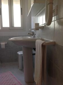 bagno bianco con lavandino e asciugamano di Hotel Ca' D'Oro a Caorle