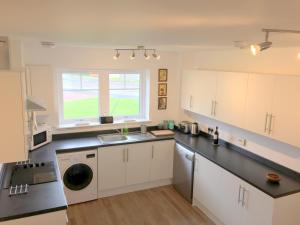 a kitchen with white cabinets and a sink and a window at Ventoux in Aviemore