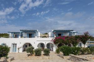 a white building with blue roofs and flowers at Ergina Summer Resort in Antiparos