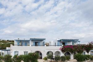 a white building with blue roofs and flowers at Ergina Summer Resort in Antiparos