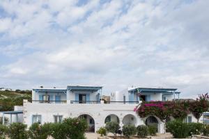 a white building with blue roofs and flowers at Ergina Summer Resort in Antiparos