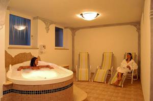a woman sitting in a bath tub in a bathroom at Hotel Scoiattolo in Selva di Val Gardena