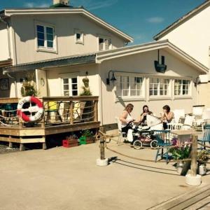 un groupe de personnes assises sur la terrasse couverte d'une maison dans l'établissement Kaikanten Kro og Rorbu, à Sennesvik