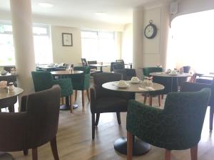 a dining room with tables and chairs and a clock at Penny Farthing Hotel & Cottages in Lyndhurst