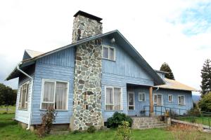 a blue house with a stone chimney at La Posada del Colono in Puerto Clocker