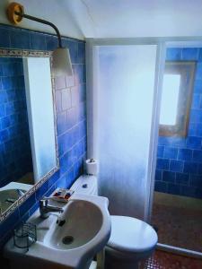 a blue tiled bathroom with a sink and a toilet at Casa Rural FuenteVieja in La Mata de los Olmos