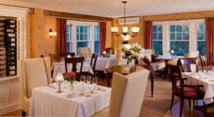 a dining room with white tables and chairs and windows at Sugar Hill Inn in Sugar Hill