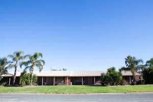 a large white house sitting in front of a palm tree at Echuca Moama Holiday Villas in Moama