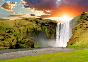 una persona parada frente a una cascada en Kornhóll, en Hvolsvöllur