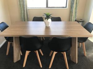 a wooden table with black chairs and a vase on it at National Park Home in National Park