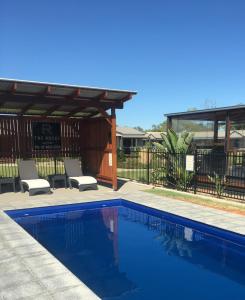 a swimming pool with two chairs and a pergola at The Rocks Motel in Charleville