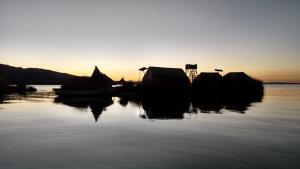 um grupo de barcos sentados na água ao pôr do sol em Uros Suyawi Titicaca Lodge em Puno