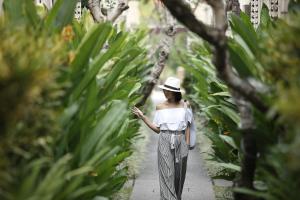 a woman walking down a path through a garden at Lalasa Villas Canggu in Canggu