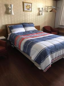 een groot bed met blauwe en witte dekens en kussens bij Melody Motor Lodge in Connellsville