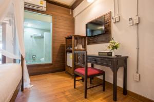 a bedroom with a desk with a red chair and a mirror at Night Bazaar Inn in Chiang Mai