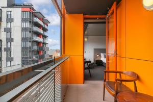 een oranje kamer met een balkon met een tafel en stoelen bij The Soho Hotel in Adelaide