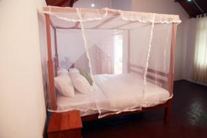 a bedroom with a canopy bed with white sheets and pillows at Sinharaja Forest Sanctuary in Deniyaya +52 photos